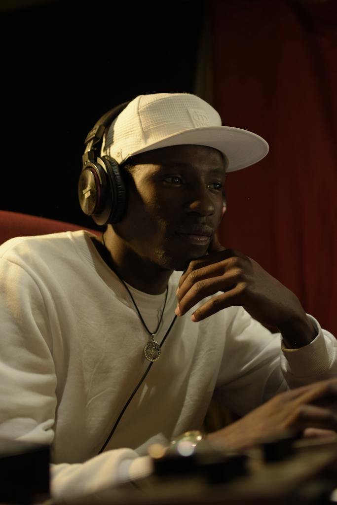 Photo of a Pensive Young Man with Headphones Sitting in a Music Studio