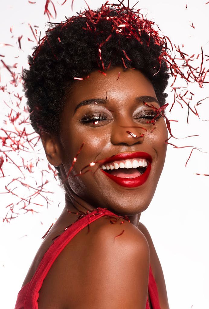 Close-up Photo of Smiling Woman with Her Eyes Closed Posing As Confetti Drops Down Her Face